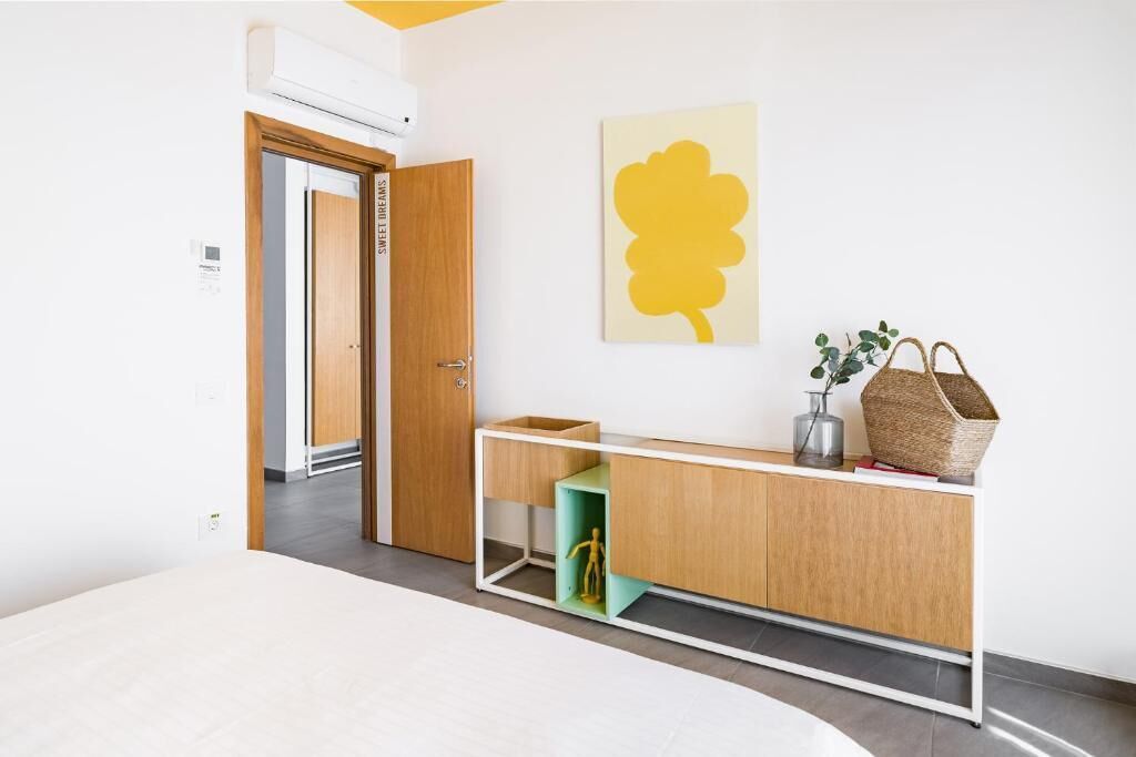 A modern room with a wooden cabinet, a green shelf, and a yellow artwork.