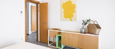 A modern room with a wooden cabinet, a green shelf, and a yellow artwork.