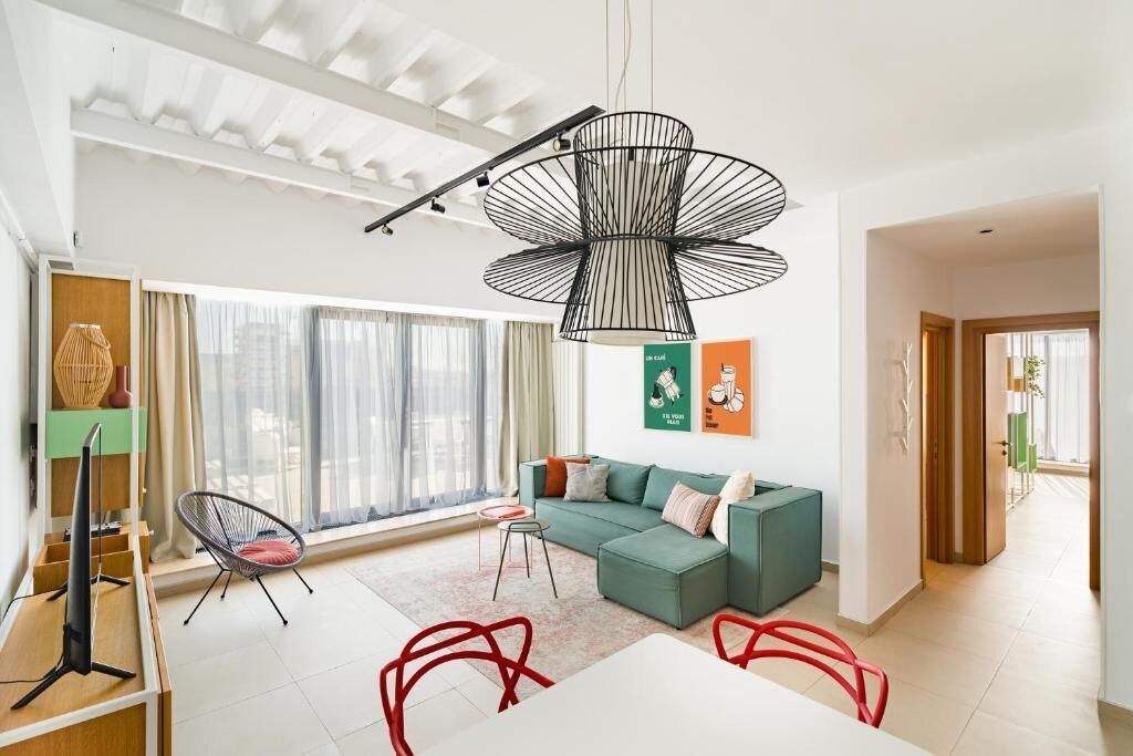 A modern living room with a sectional sofa, a dining table, and a unique black pendant light.