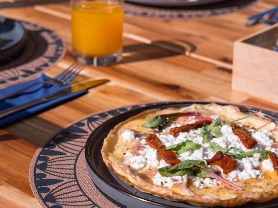 Une table à manger avec une assiette de nourriture, un verre de jus d’orange et une fourchette.