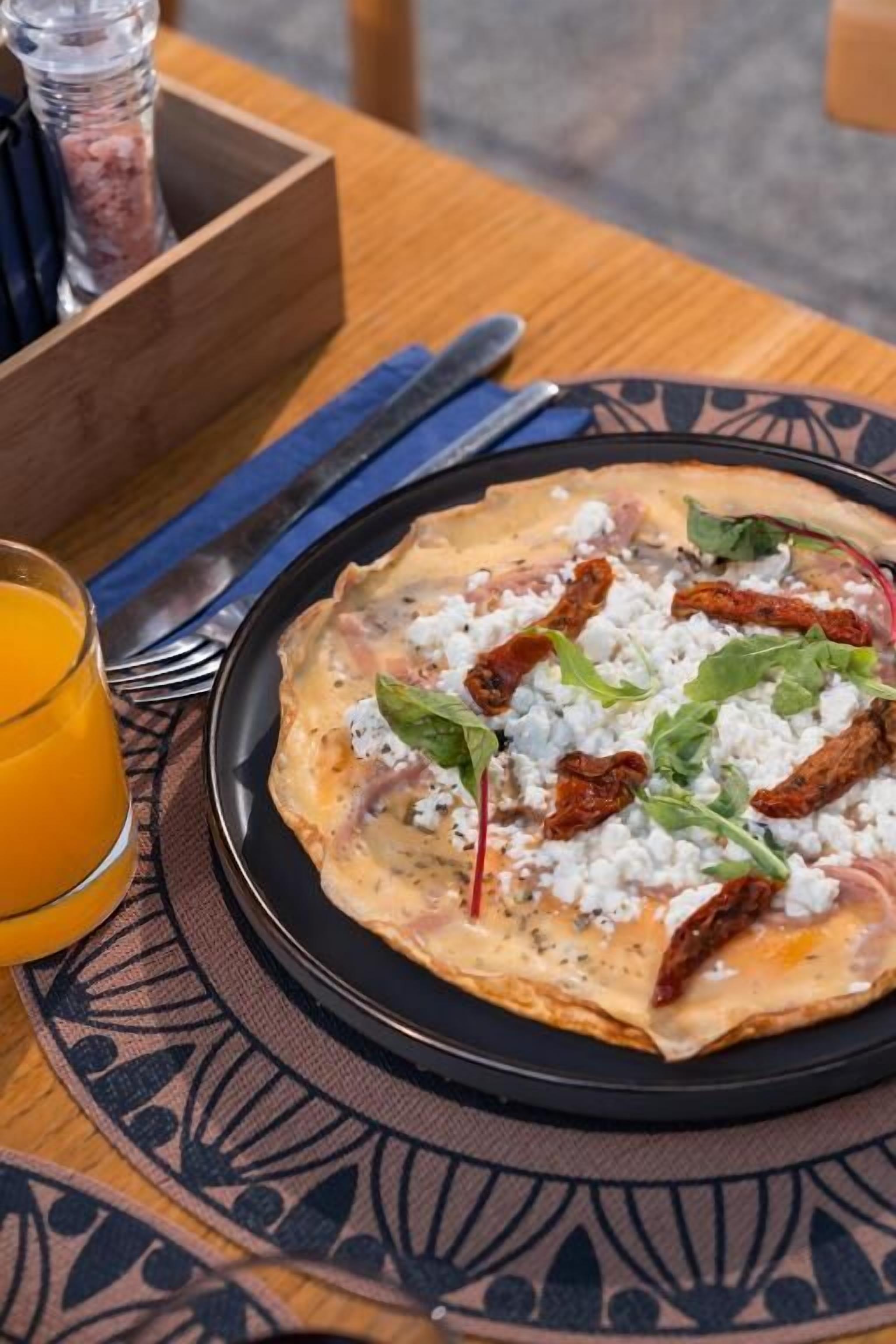Un plato de comida con un vaso de jugo de naranja sobre una mesa.