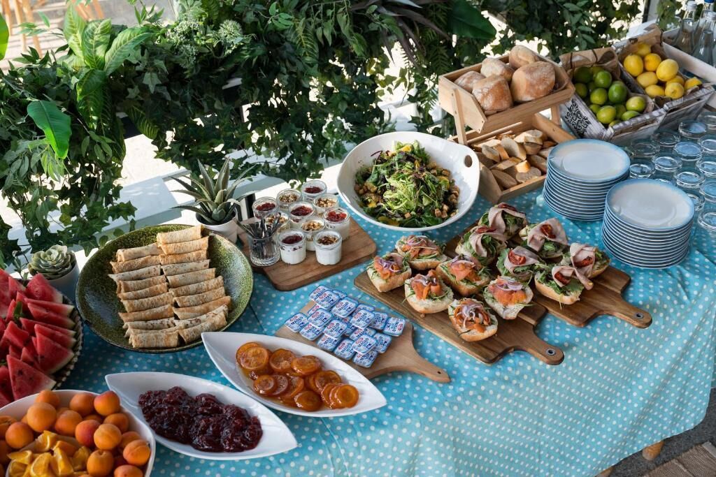 A table set with various food items, including sandwiches, fruits, and condiments.