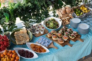 Una mesa dispuesta con diversos alimentos, entre ellos sándwiches, frutas y salsas.