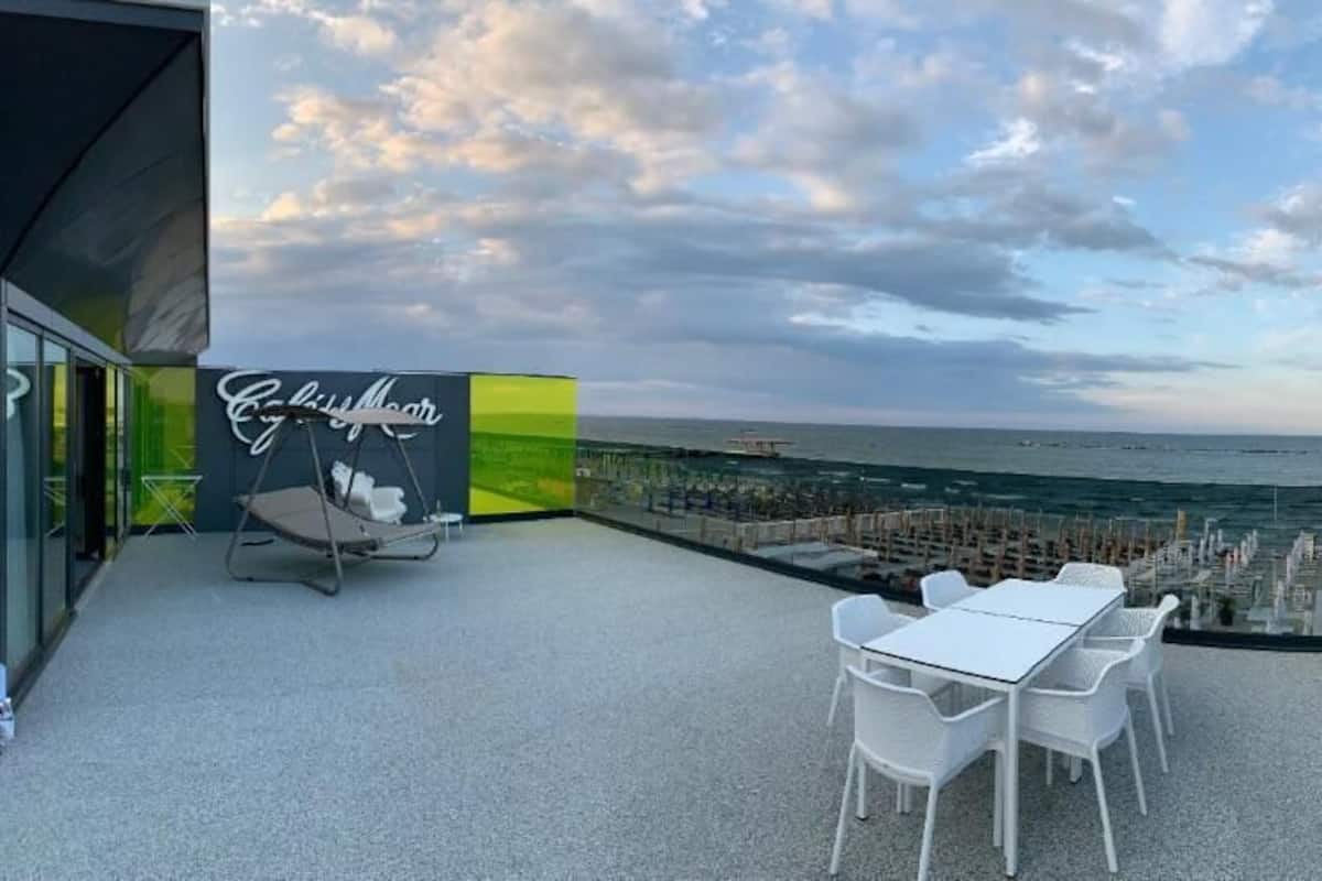 A rooftop terrace with a view of the sea, a seating area with tables and chairs, and a sign that reads "Culinary Moon".