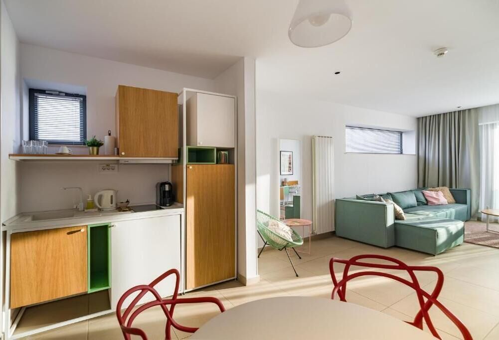 A compact living space with a kitchenette, a dining area, and a seating area with a sofa and chairs.