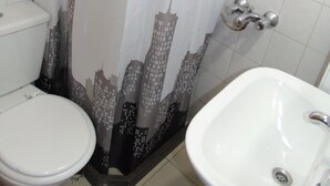 A bathroom with a toilet, a sink, and a shower curtain with a cityscape design.