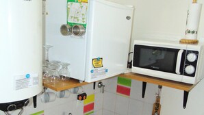 A compact kitchen with a PHILCO water heater, a microwave, a kettle, and a sink.