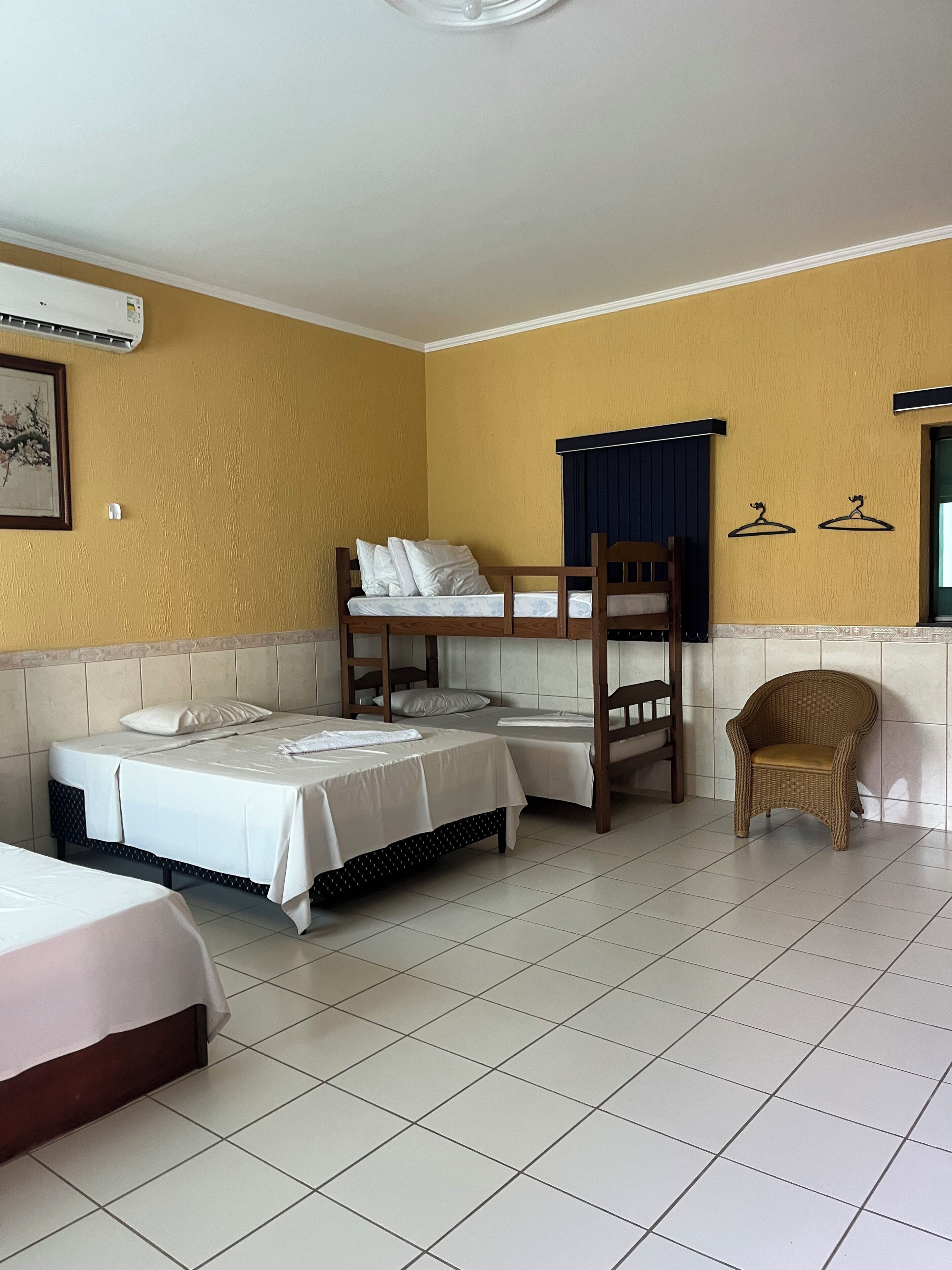 Una habitación con literas, una silla y un aire acondicionado montado en la pared.