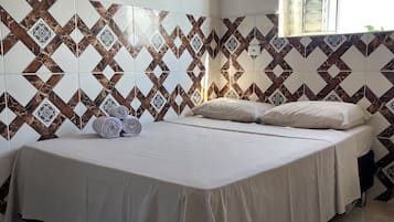 A room with a bed, a window, and patterned wall tiles.