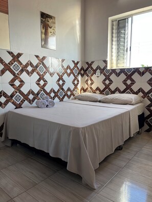 A room with a bed, a window, and patterned wall tiles.