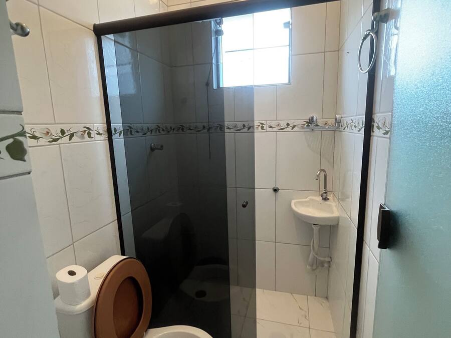 Un baño con ducha envuelta en vidrio, inodoro y lavamanos.
