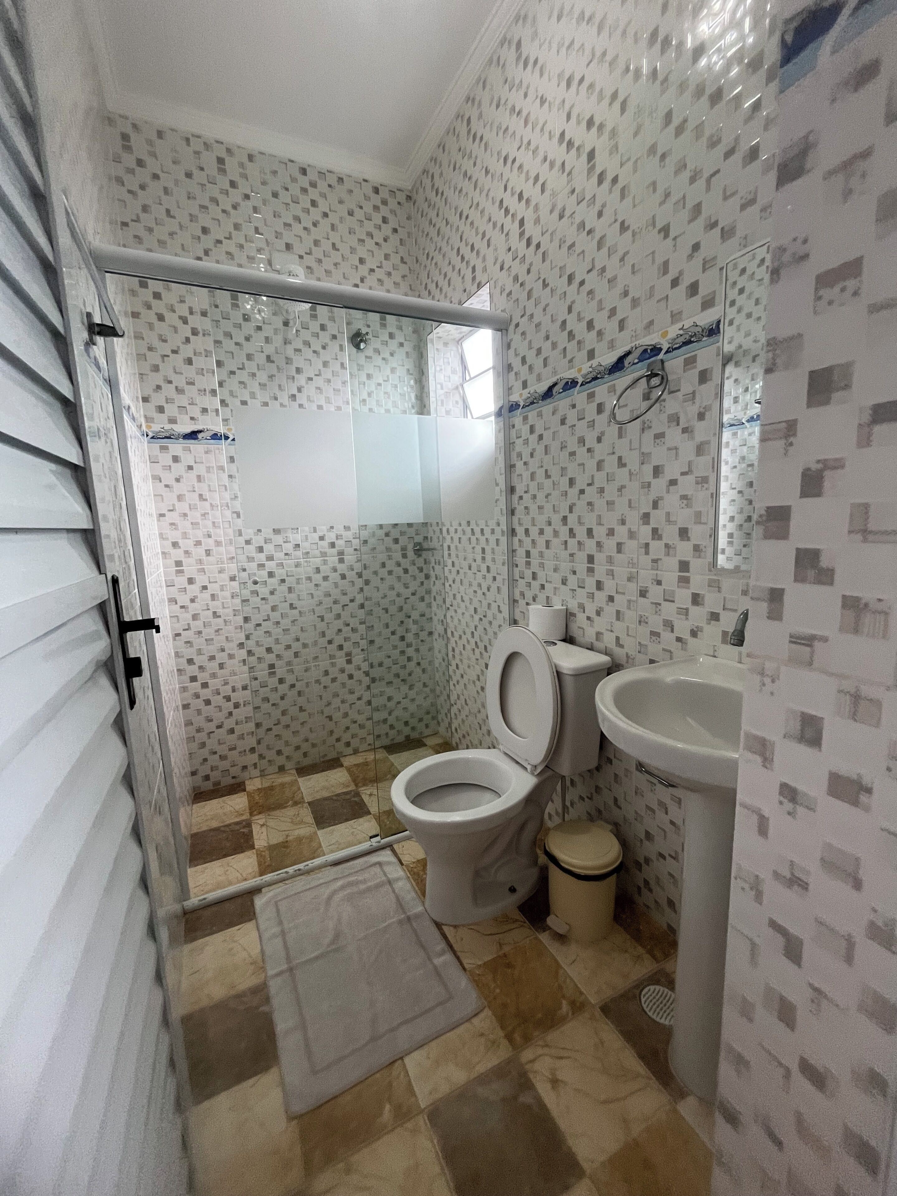 Une salle de bain avec douche, toilettes, lavabo et murs carrelés.