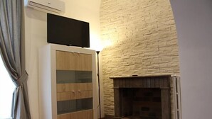 Una habitación con chimenea, televisor montado en la pared y un aparador con puertas de cristal.