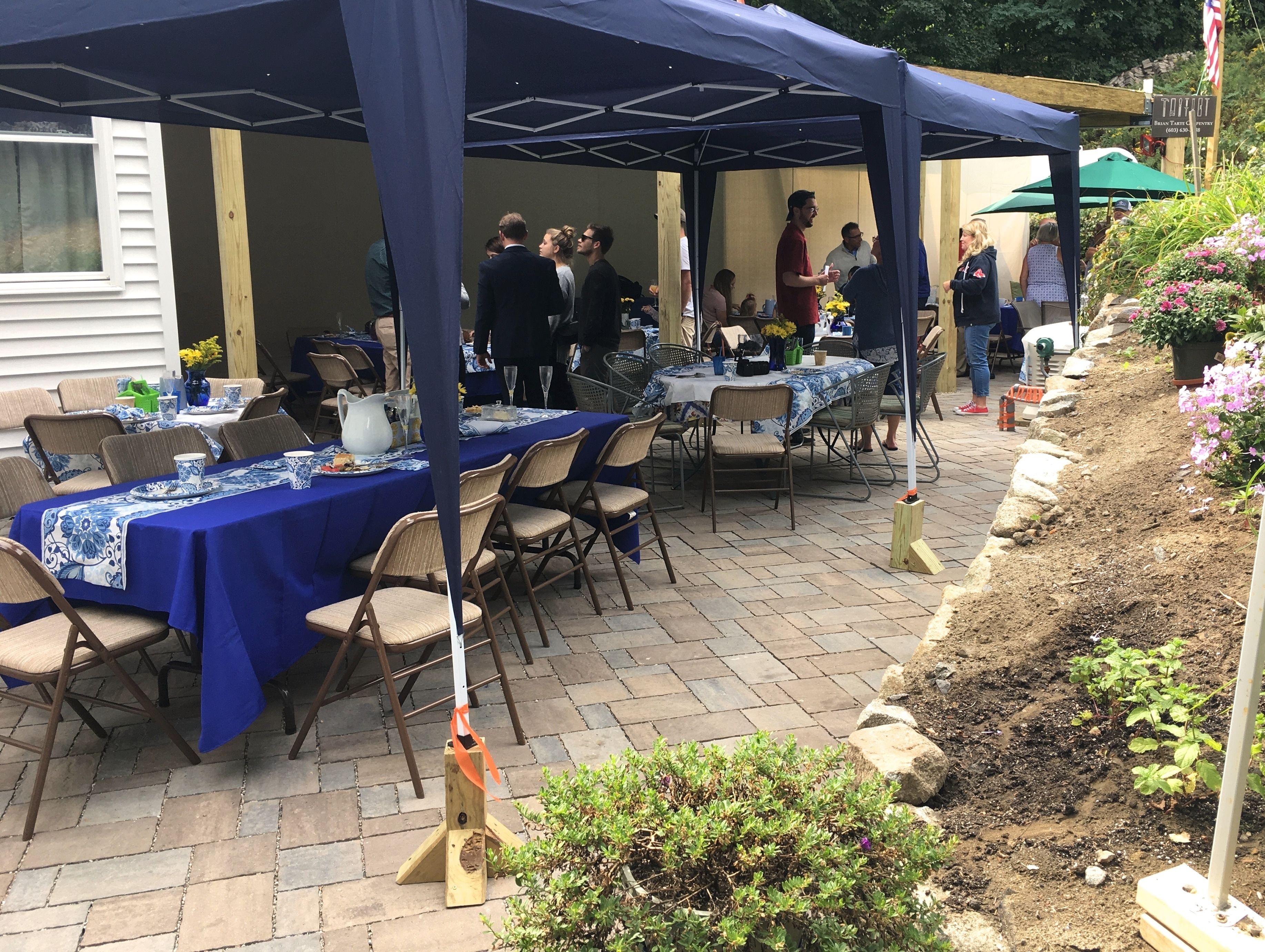 An outdoor patio area with tables covered in blue tablecloths, surrounded by chairs.