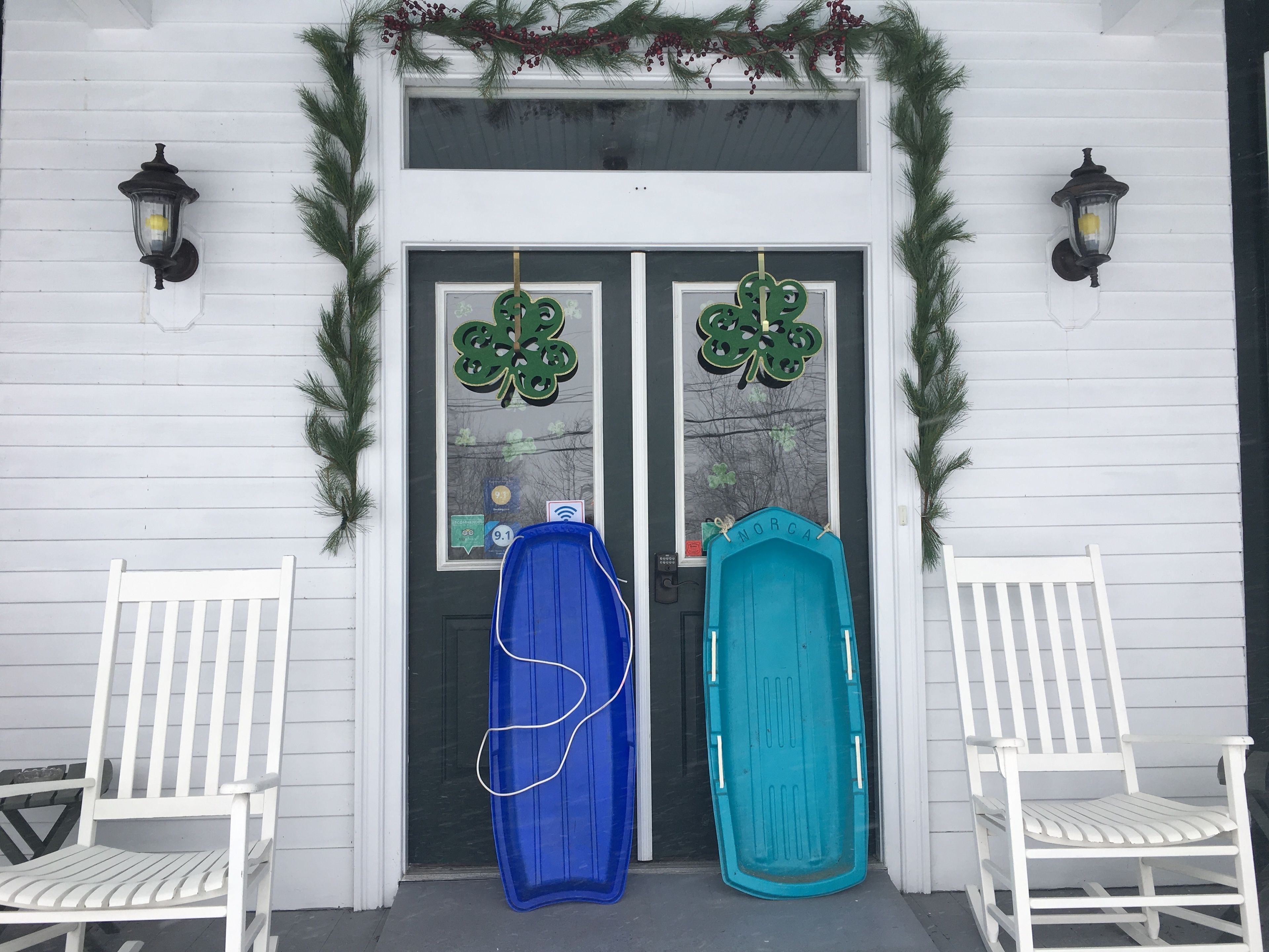 Un bâtiment blanc doté de deux portes, chacune ornée d’un motif en forme de trèfle vert.