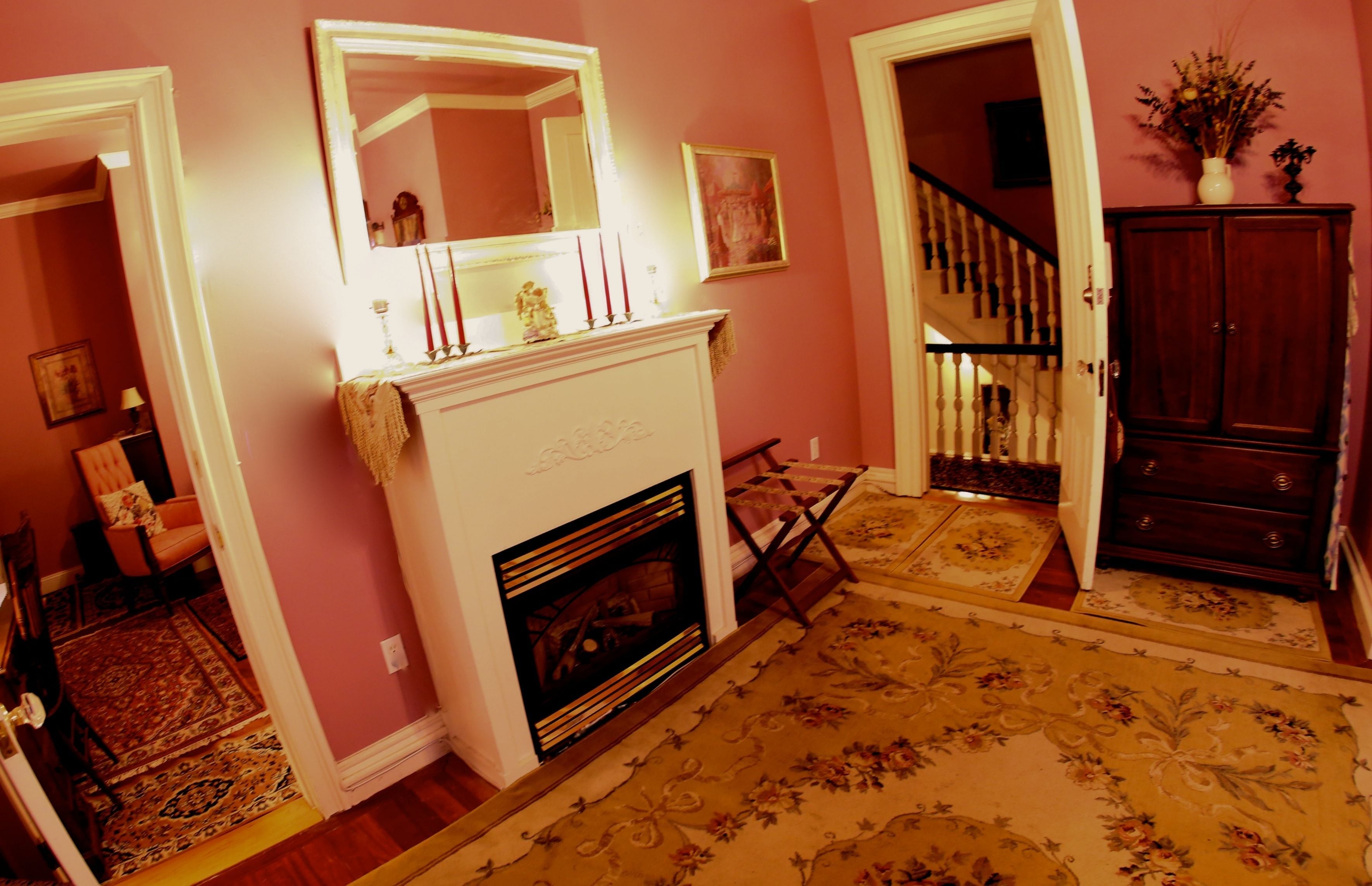 Un couloir avec une cheminée, un miroir, un escalier et une armoire.