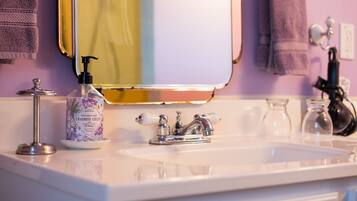 A bathroom sink with a mirror, a lavender fields hand soap dispenser, and a faucet.