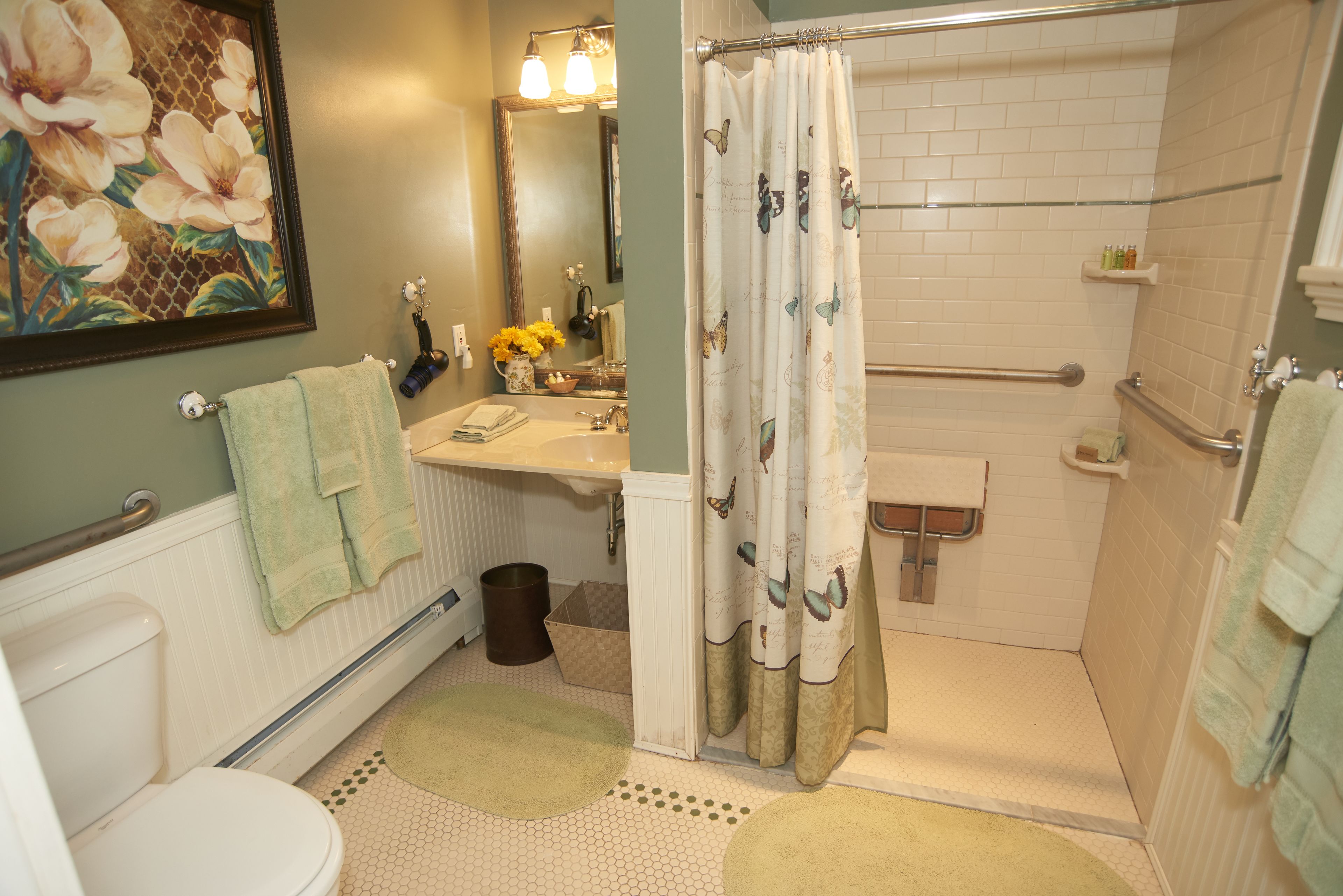 A bathroom with a toilet, sink, shower, and a large mirror.