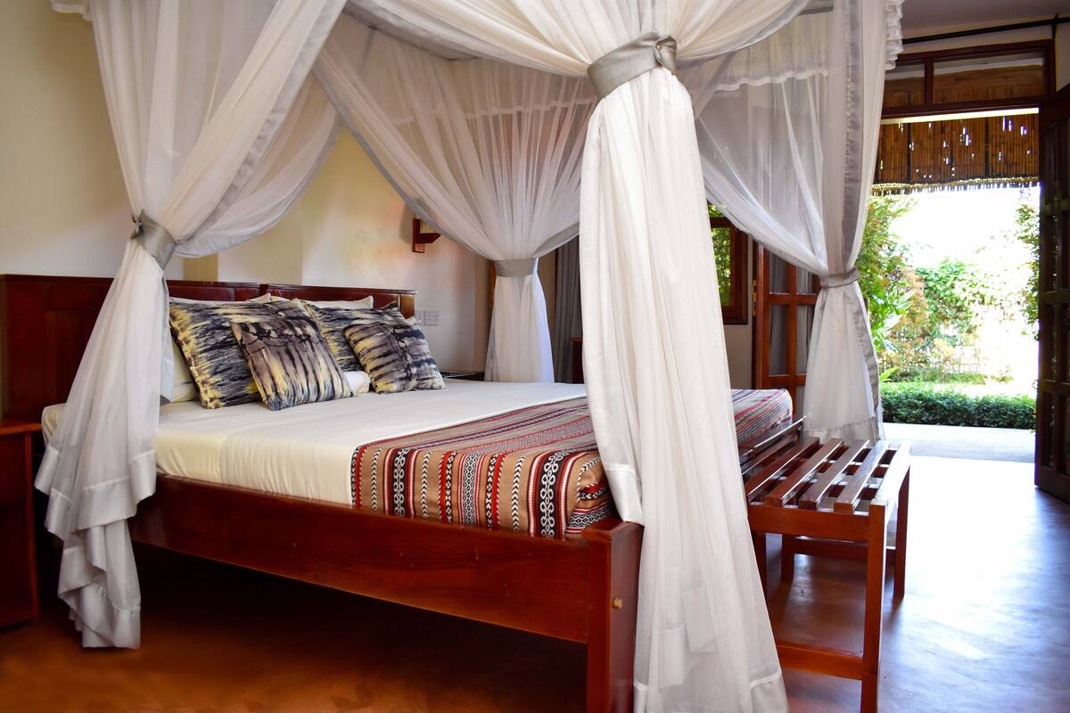 A four-poster canopy bed with a wooden frame and a patterned bedspread.