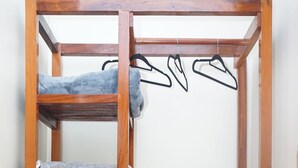 Een houten garderobe met meerdere planken en een hanggedeelte, een rieten mand en een houten vloer.
