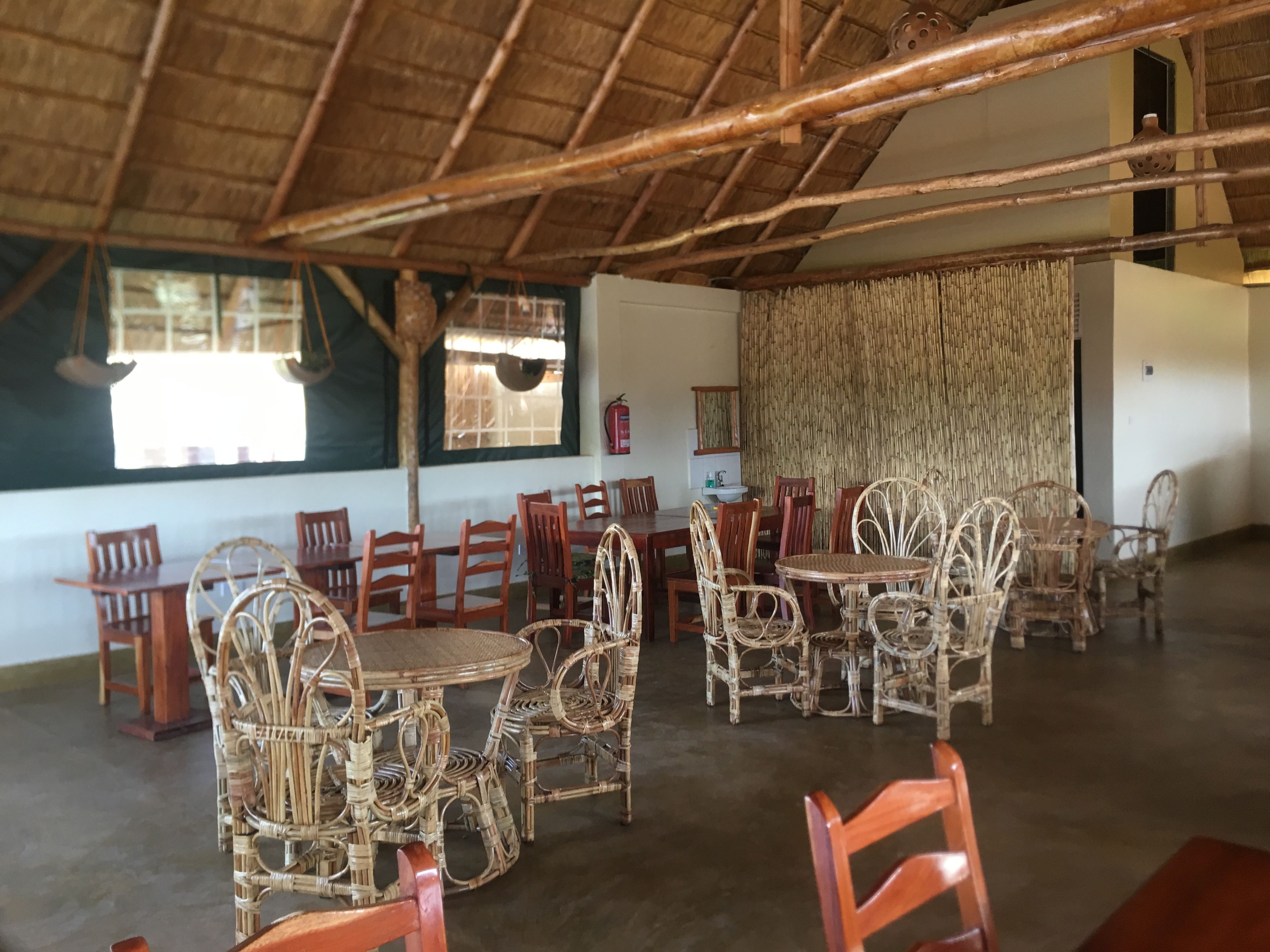 Un comedor con mobiliario de mimbre y techo de paja.