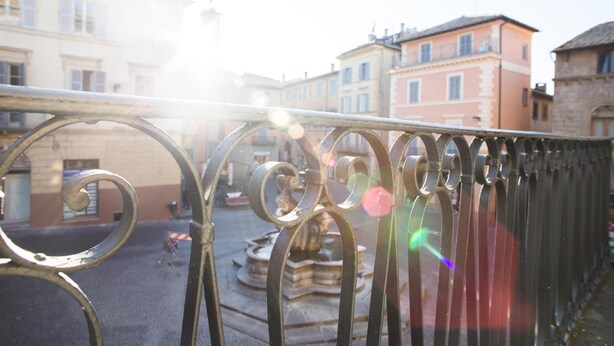 A courtyard with a fountain, surrounded by buildings with classical architecture. - Le Erbe Guest House (Viterbo)