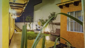A courtyard with a staircase leading to an upper level, surrounded by plants and a small table. - Posada Antiguo Camino Real (Xalapa)