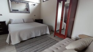 A bedroom with a bed, a nightstand, a dresser, a mirror, a wooden door, and a sofa. - Posada Antiguo Camino Real (Xalapa)