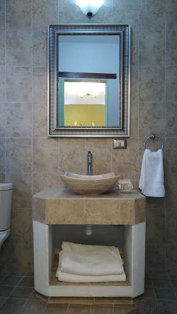 A bathroom with a large mirror, a vessel sink, and a towel rack.