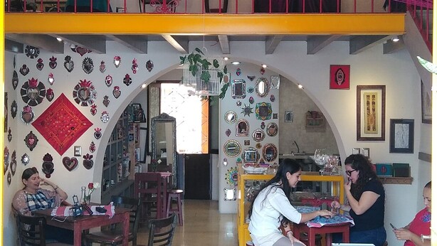 A two-story cafe with a vibrant interior, featuring a mix of seating arrangements and decorative elements like mirrors and wall art. - Posada Antiguo Camino Real (Xalapa)