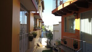 A narrow outdoor corridor with balconies, potted plants, and a staircase leading to an upper level. - Posada Antiguo Camino Real (Xalapa)