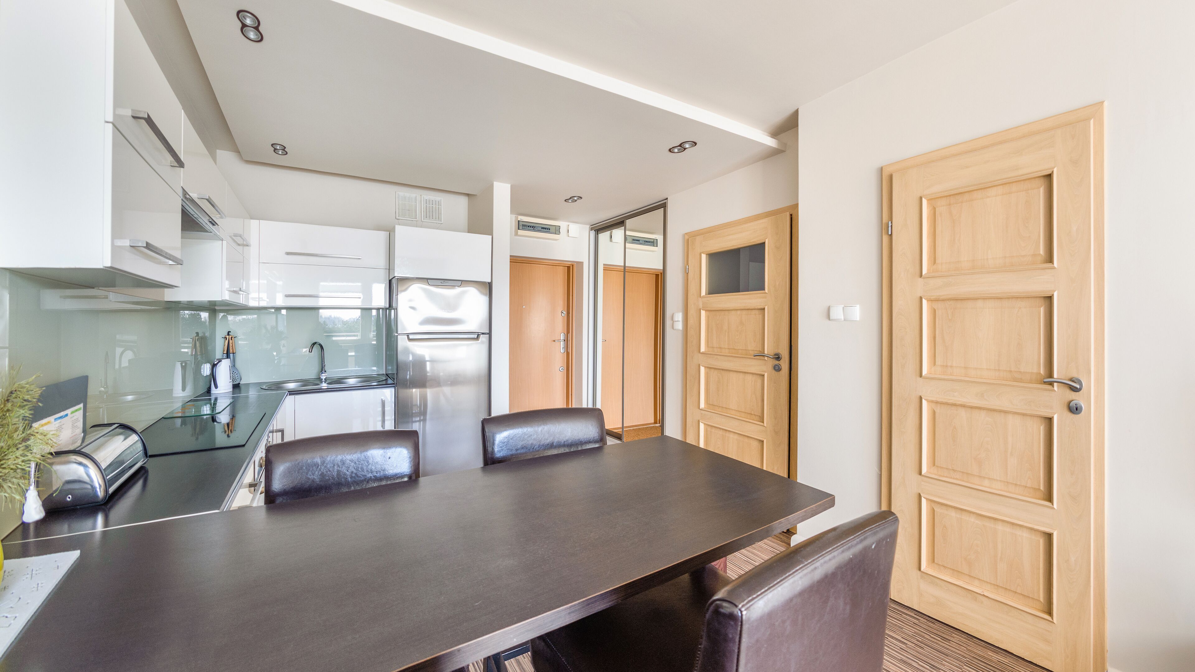 Una cocina moderna con comedor, que incluye una mesa y sillas, y puertas de madera.