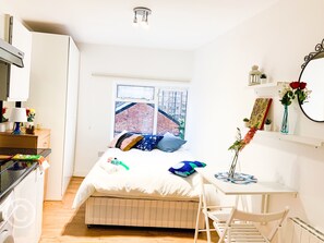 A compact bedroom with a bed, bedside table, and a window with a view of a brick building.