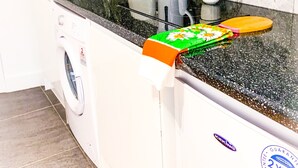 A compact kitchen with a washing machine, a coffee maker, and a sink. - Cricklewood Studio Flats (London)