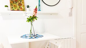 A white desk with a mirror, two chairs, and a vase with flowers. - Cricklewood Studio Flats (London)