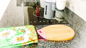 A kitchen with a stainless steel sink, a coffee maker, a vase with flowers, and a cutting board. - Cricklewood Studio Flats (London)
