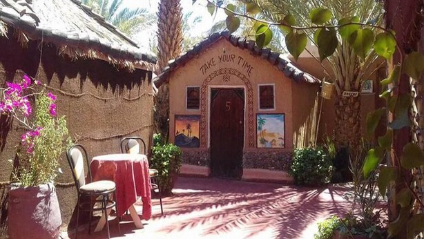 A small building with a thatched roof and a sign that reads "TAKE YOUR TIME". - Hostel take your time 4225 (Zagora)