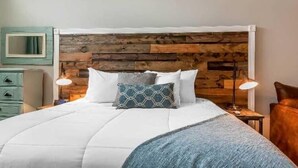 A bedroom with a wooden headboard, white bedding, and two bedside lamps. - Lakes Inn at Dunvilla (Pelican Rapids)