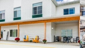 A white building with a covered porch, outdoor seating, and a visible interior dining area. - Lakes Inn at Dunvilla (Pelican Rapids)