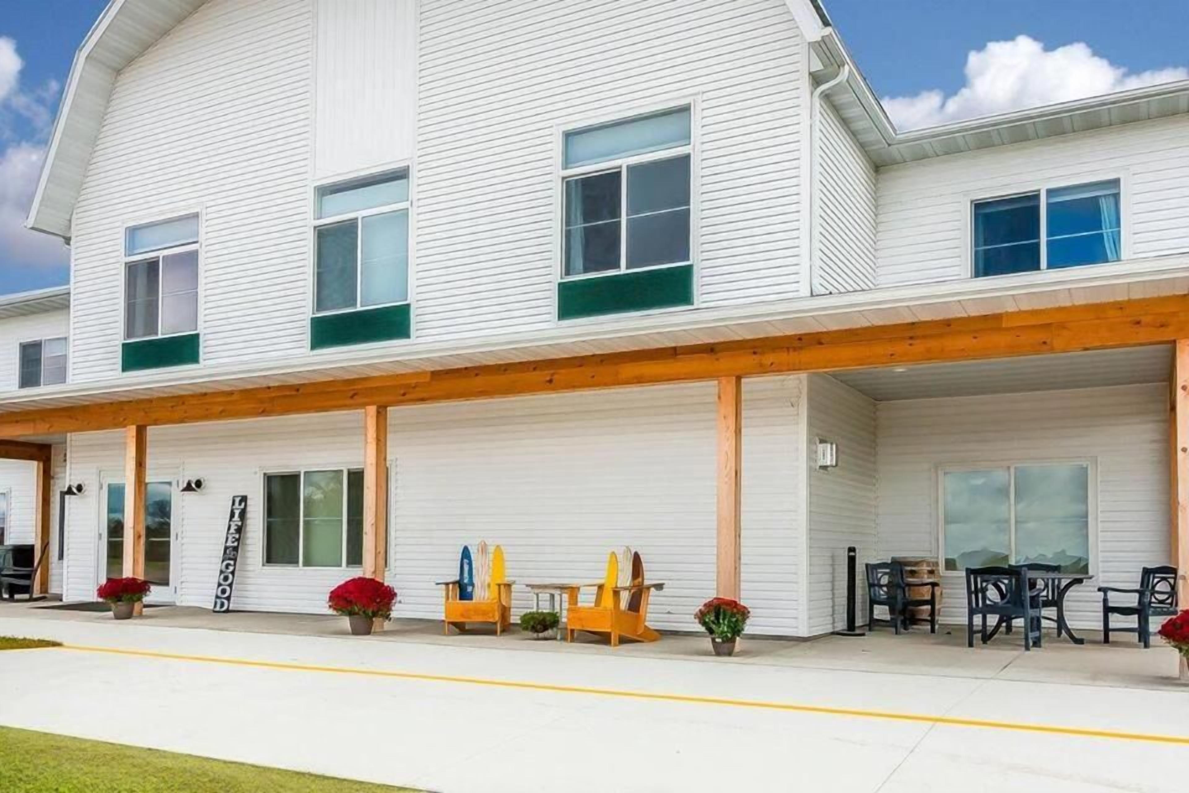 Un bâtiment à deux étages doté d’un porche avant couvert, d’un espace extérieur aménagé pour s’asseoir et d’une enseigne sur laquelle on peut lire : « LA VIE EST BELLE ».