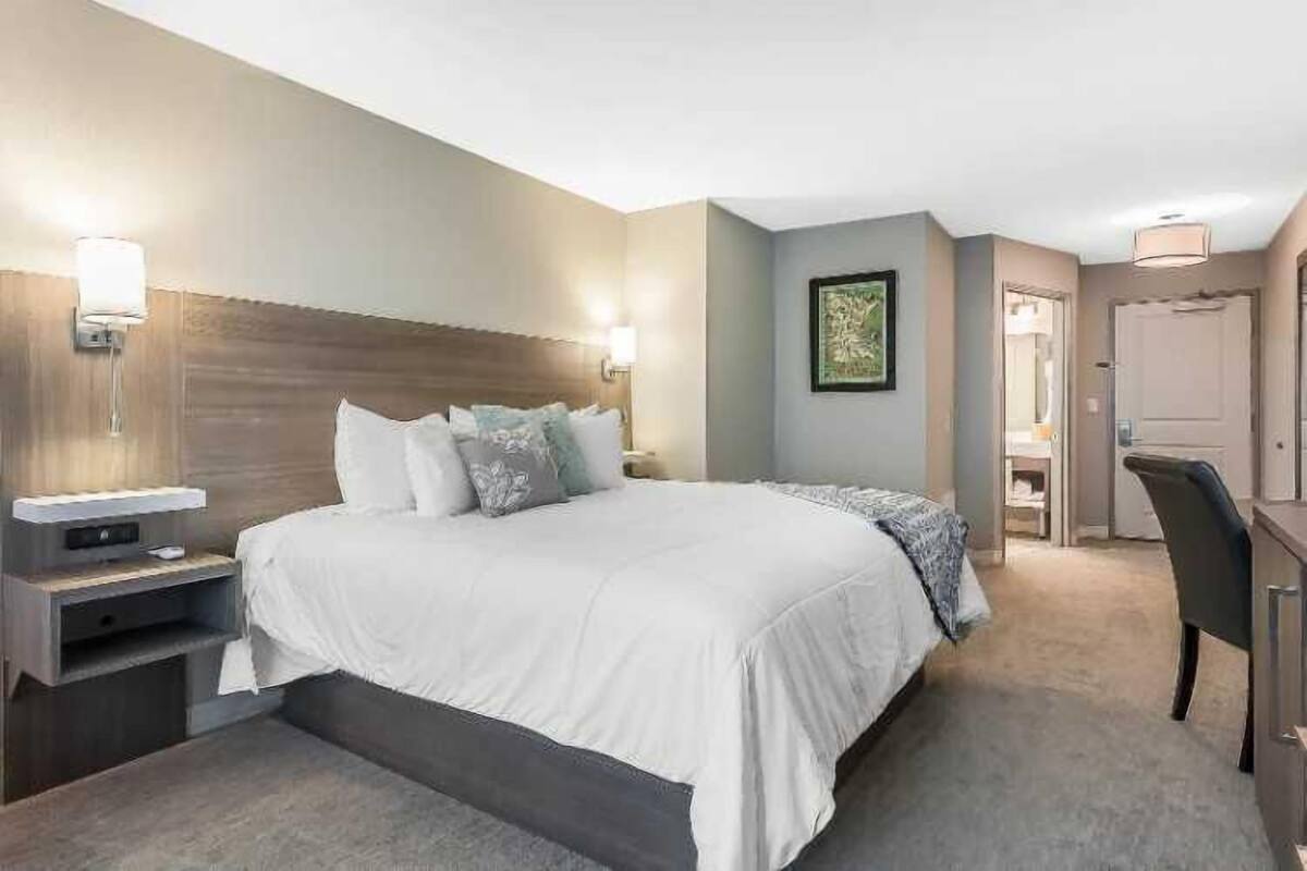 Une chambre d’hôtel bien aménagée, avec un grand lit, des tables de chevet, un bureau et une chaise.