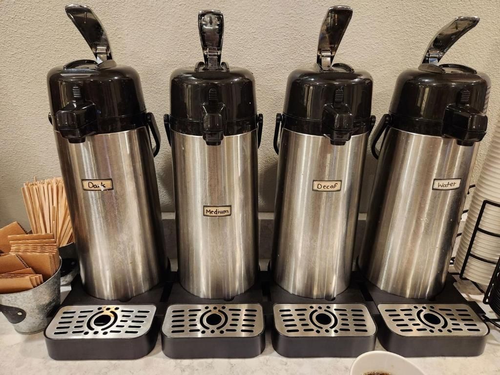 Four stainless steel water dispensers labeled 'Day's Medium' and 'Decaf' on a countertop.