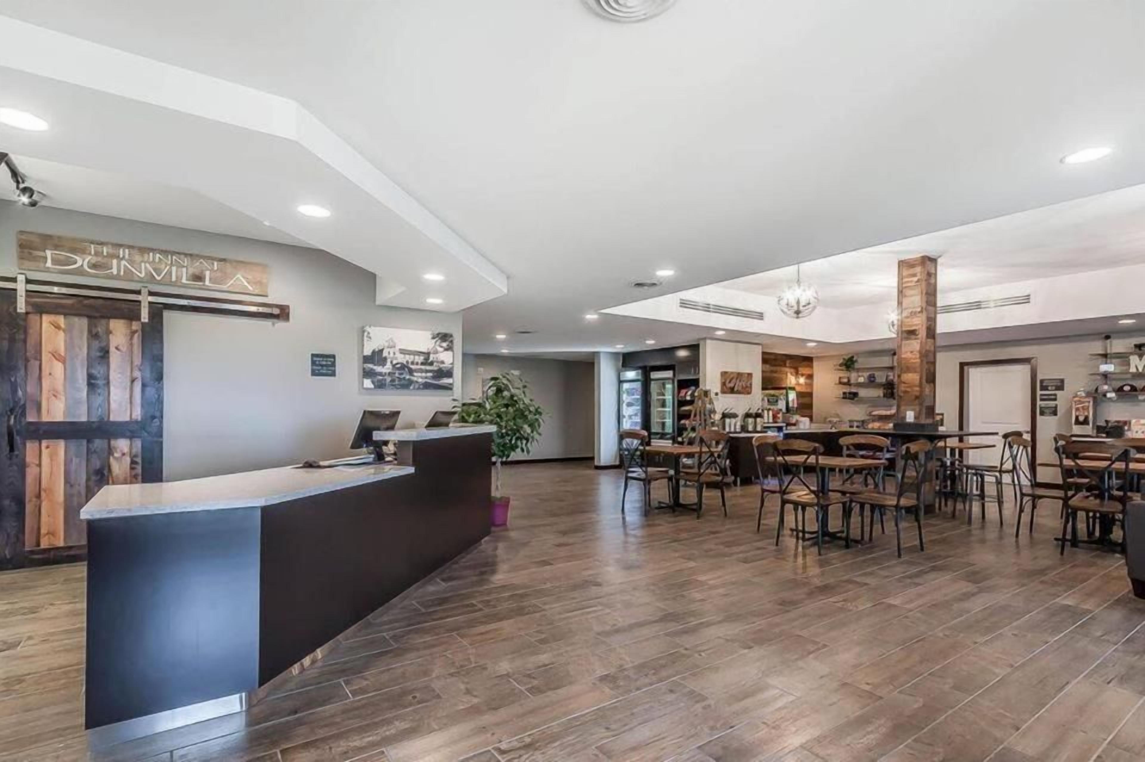 A modern hotel lobby with a reception desk, seating area, and a large plant.
