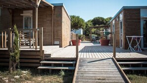 En træhytte med terrasse, en lille veranda og en sti til en anden hytte.