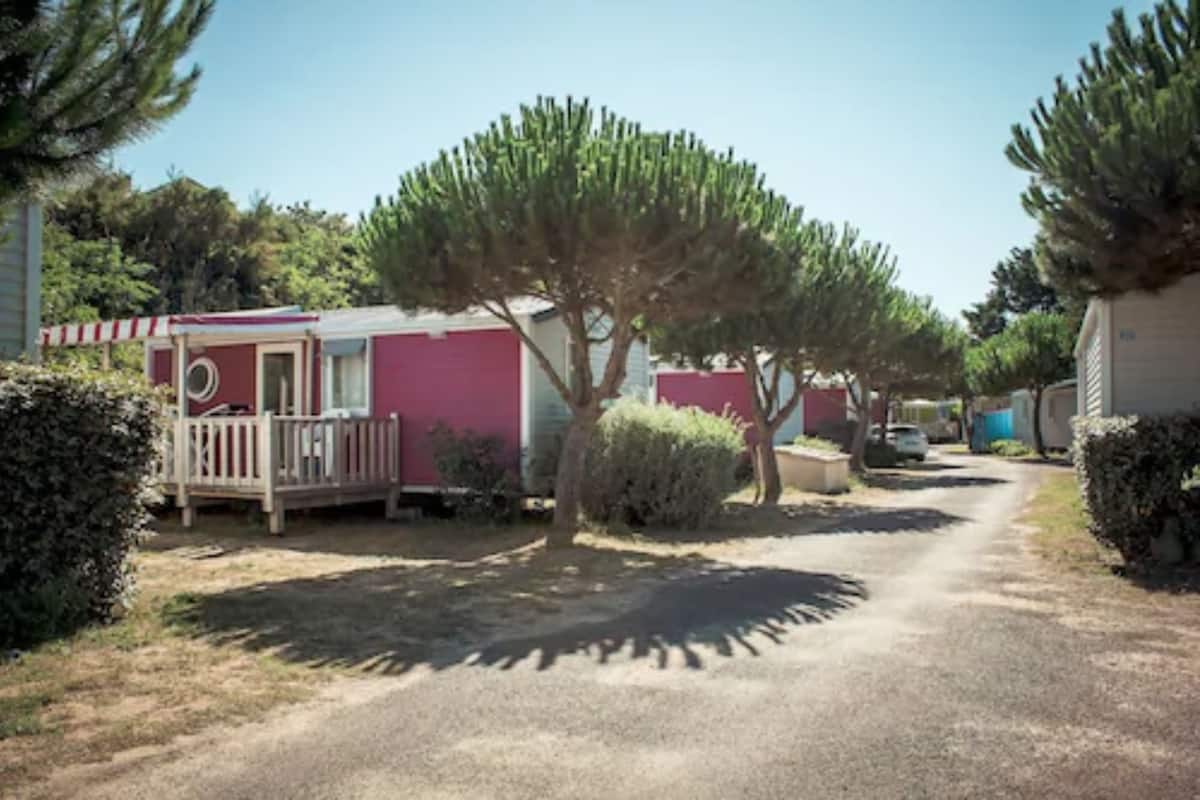 Een rij mobiele woningen met een grindpad en schaarse begroeiing.