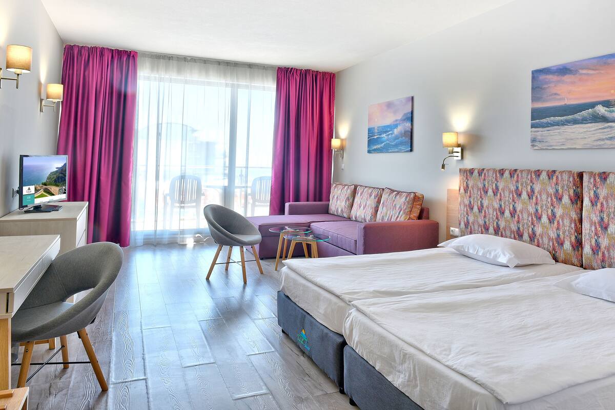 Ett modernt hotellrum med en stor säng, en soffa, ett skrivbord och en stol.
