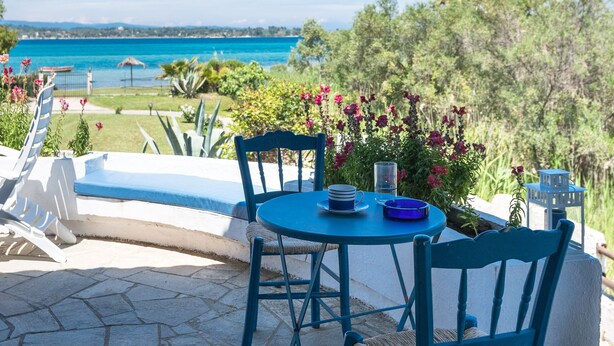 Eine Terrasse mit Tisch und Stühlen, mit Blick auf einen Pool und eine schöne Aussicht.