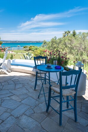A patio with a table and chairs, overlooking a pool and a scenic view. - Vourvourou Villa Mare Verde by Luxlikehome (Βουρβουρού)