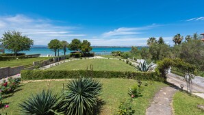 Ein angelegter Garten mit einem Weg, der zu einer Sitzgelegenheit führt, mit Blick auf ein Gewässer.