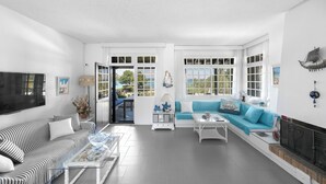 Ein geräumiges Wohnzimmer mit einem gestreiften Sofa, einem blauen Sofa und einem Kamin.